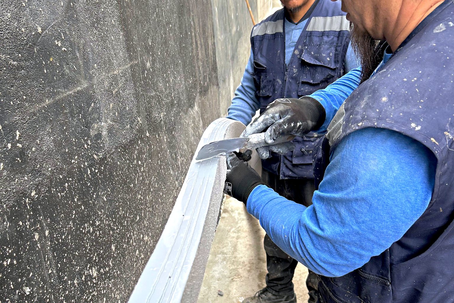 Cuadrilla de PROTEQ instalando la media caña en el encuentro entre muro y losa